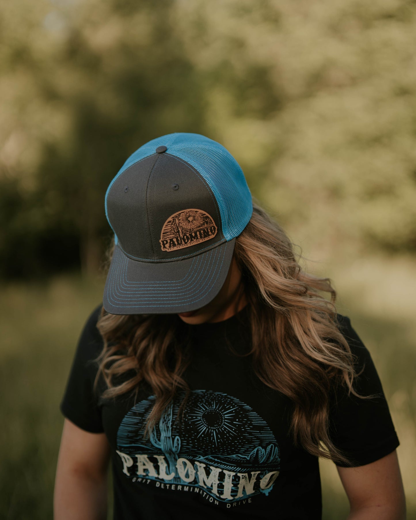 Person wearing a cap and black t-shirt with 'Palomino' branding in a forest setting